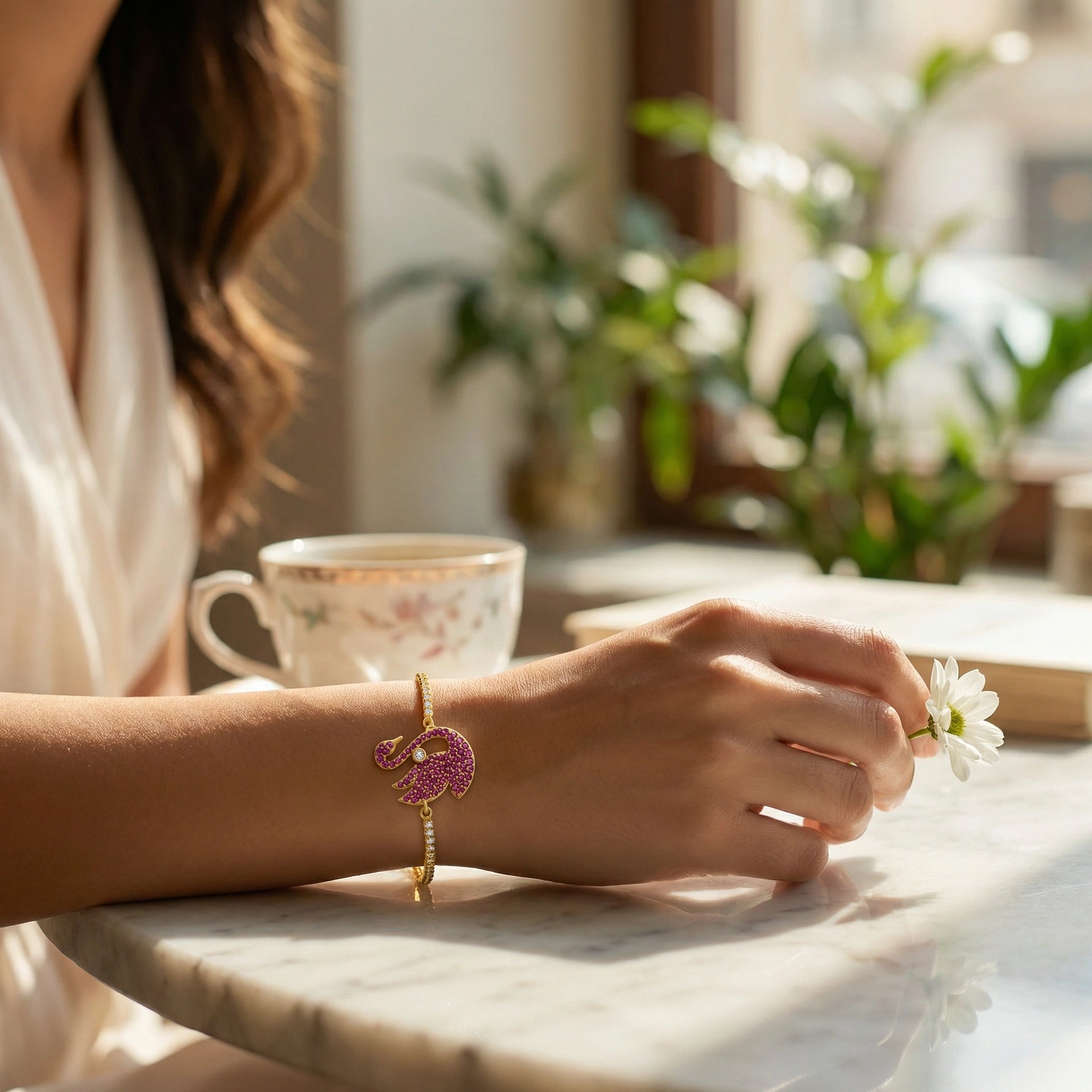 Person holding a flower with 18k gold plated  bracelet on a table in a bright room with plants