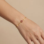 18k Gold plaetd bracelet with a floral design on a wrist against a beige background