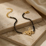Black beaded bracelet with 18k gold plated clasp and decorative element on a marble surface
