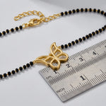 18k Gold plated  butterfly pendant on a black beaded chain with a ruler for scale on a light gray background