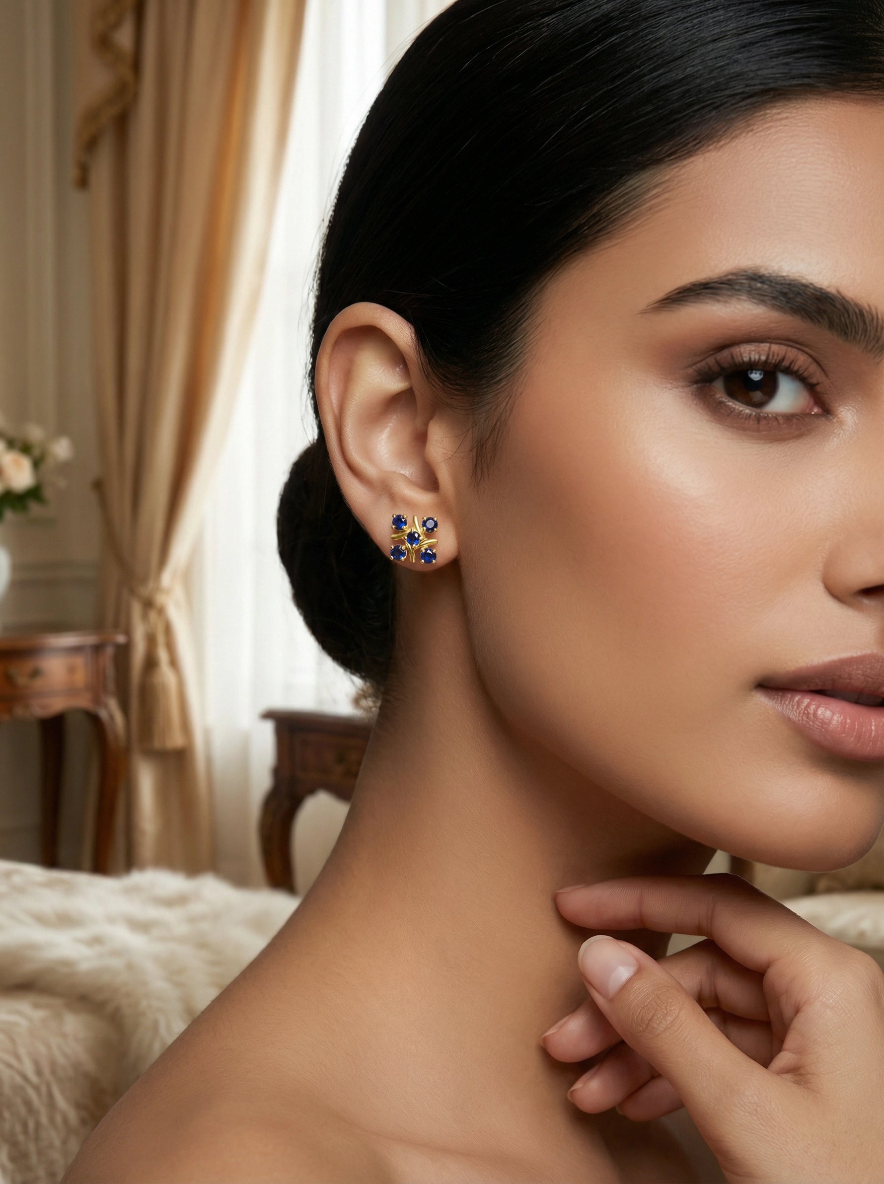 Woman wearing a pair of 18k gold plated   earrings with a blurred indoor background
