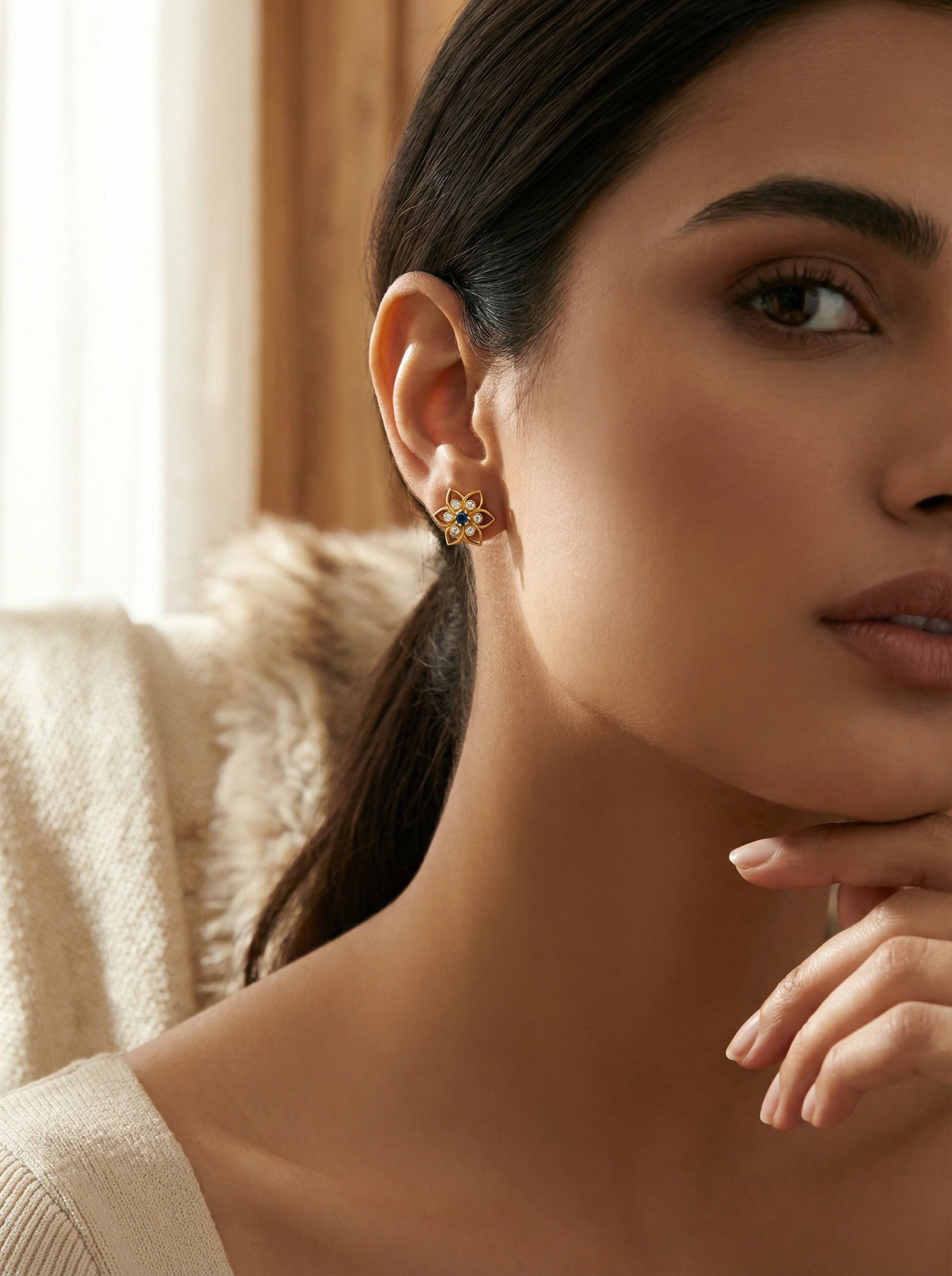 Close-up of a woman wearing a 18k  gold plated  earring with a gemstone, indoors.