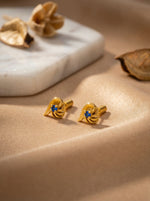 18k Gold plated earrings with blue stones on a beige surface