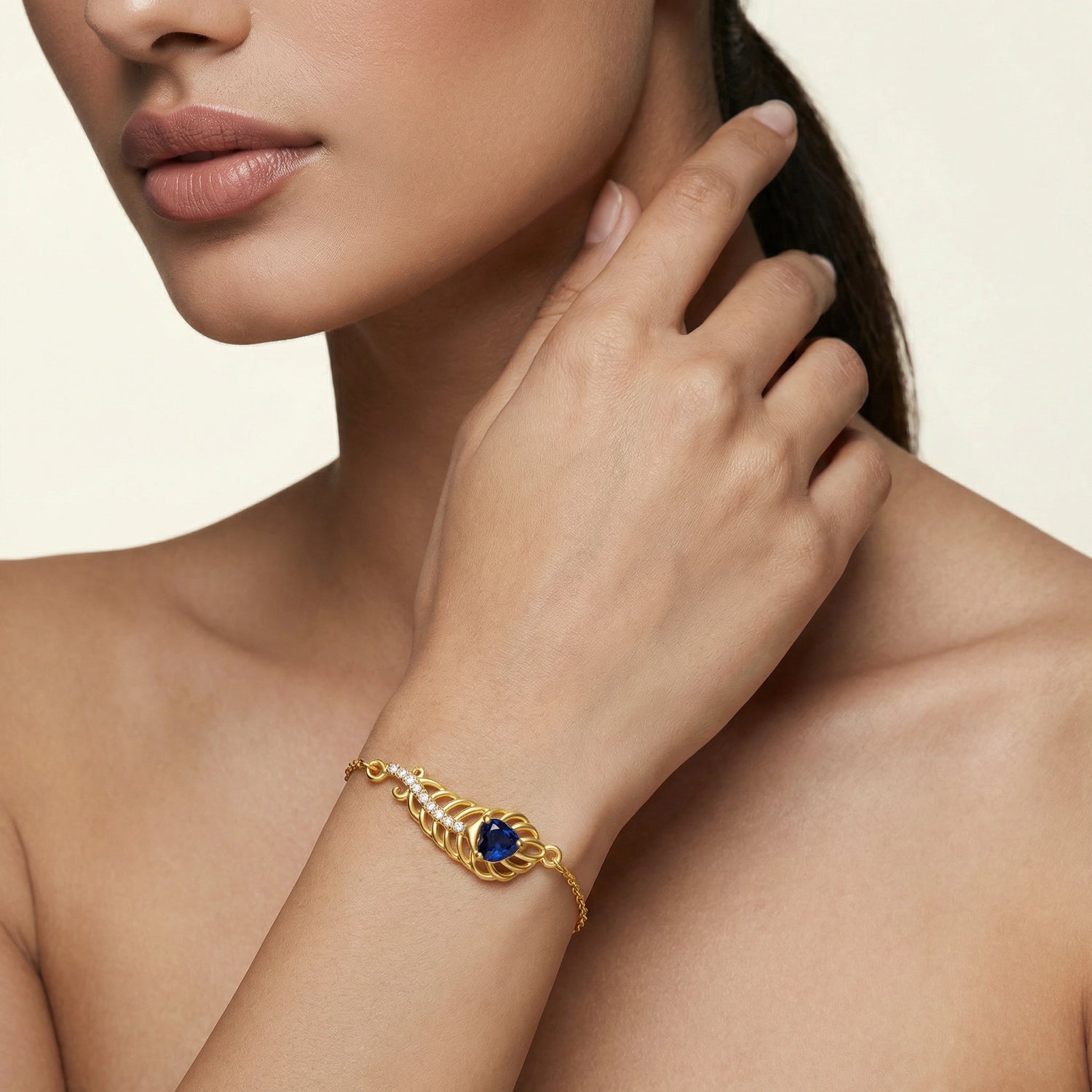 18k Gold plated bracelet with a blue gemstone on a model's wrist against a neutral background