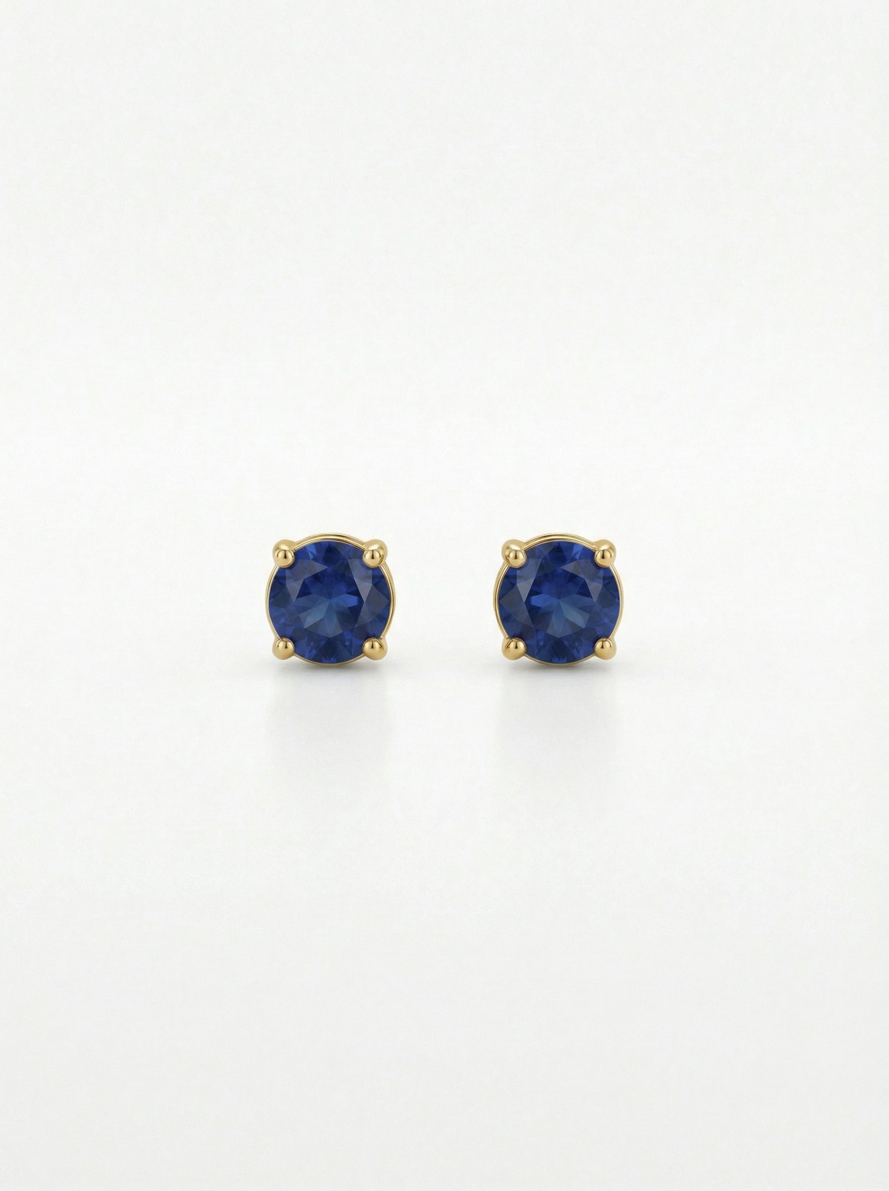 Pair of 18k gold plated earrings with blue gemstones on a white background