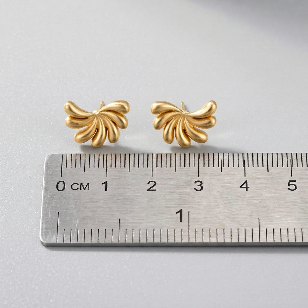 18k Gold plated butterfly-shaped earrings on a ruler for scale on a light gray background