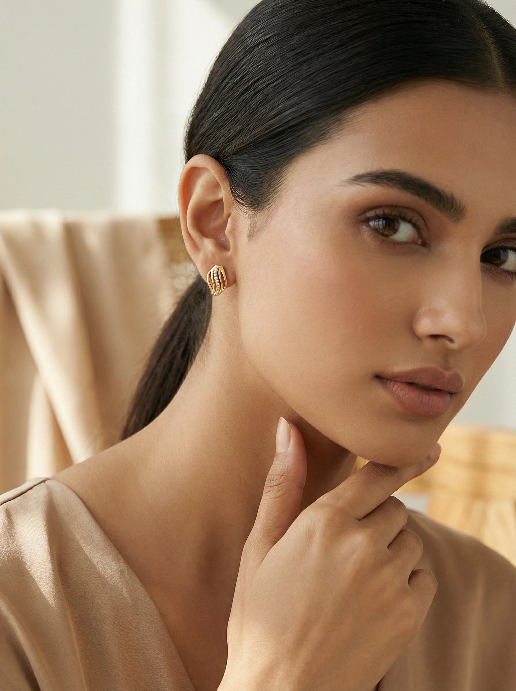 Woman wearing 18k  gold plated earrings with a neutral background