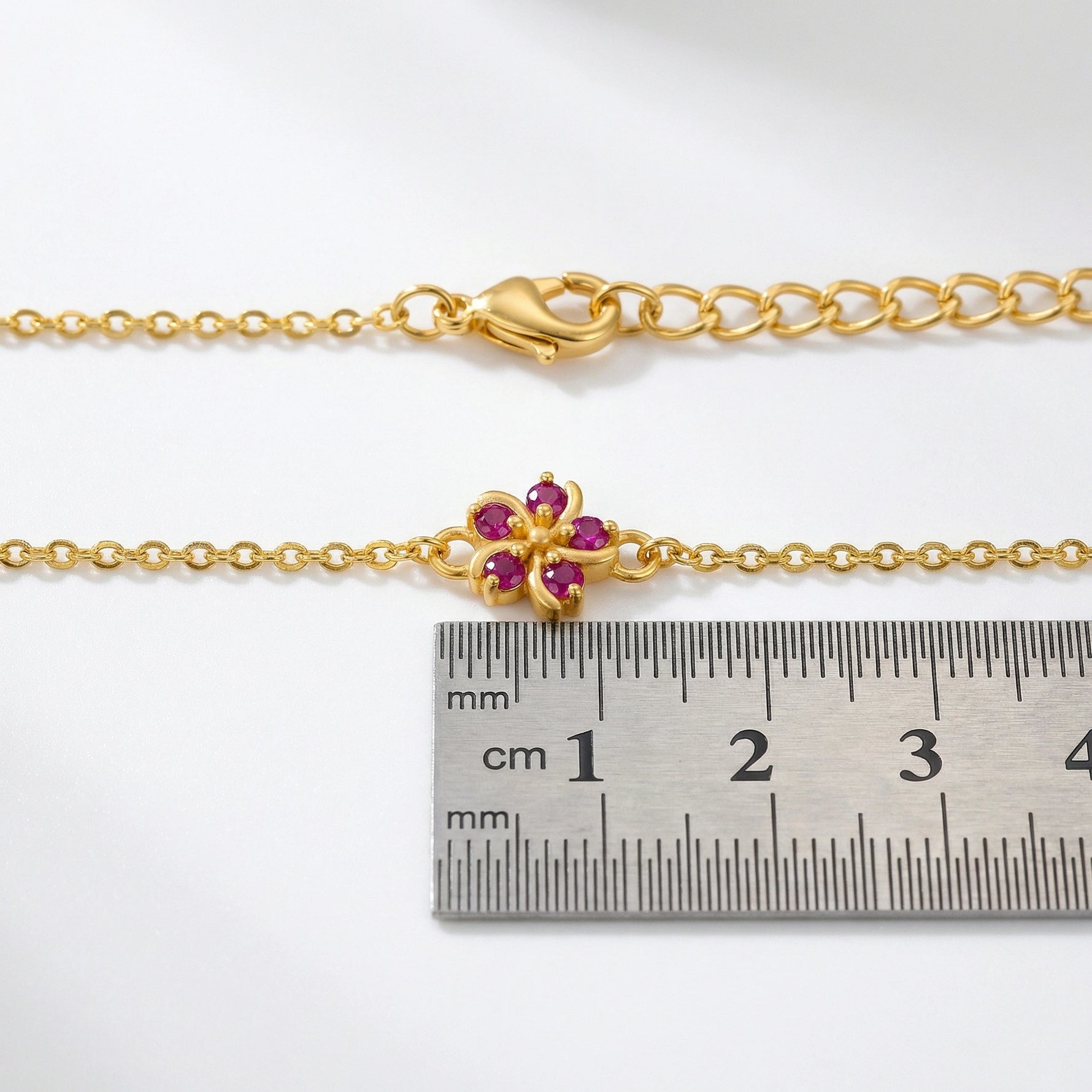 18k Gold  plated bracelet with a floral clasp next to a ruler for size reference on a white background