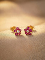 18k Gold plated earrings with red gemstones on a beige surface