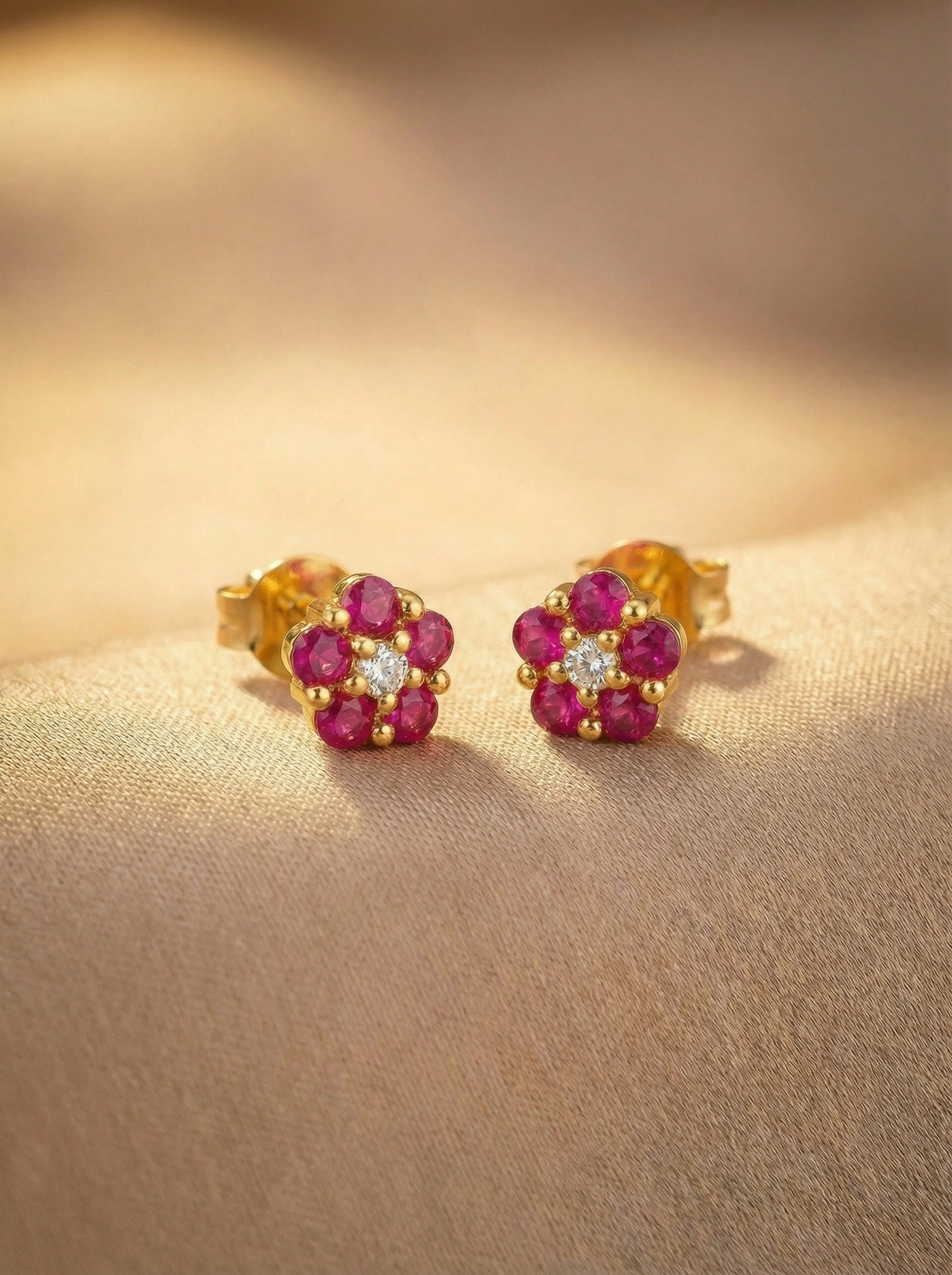 18k Gold plated earrings with red gemstones on a beige surface