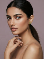 Woman wearing green earrings 18k gold plated against a neutral background 