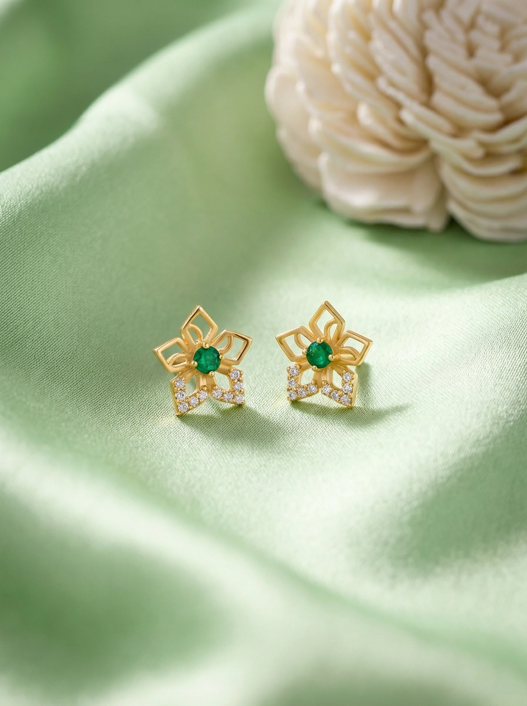 18k Gold plated flower-shaped earrings with clear stones on a green  fabric background