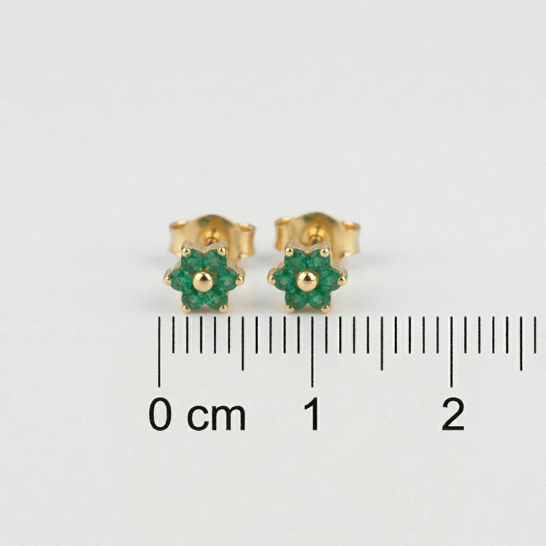 18k Gold plated earrings with green gemstones on a white background with measurement scale.