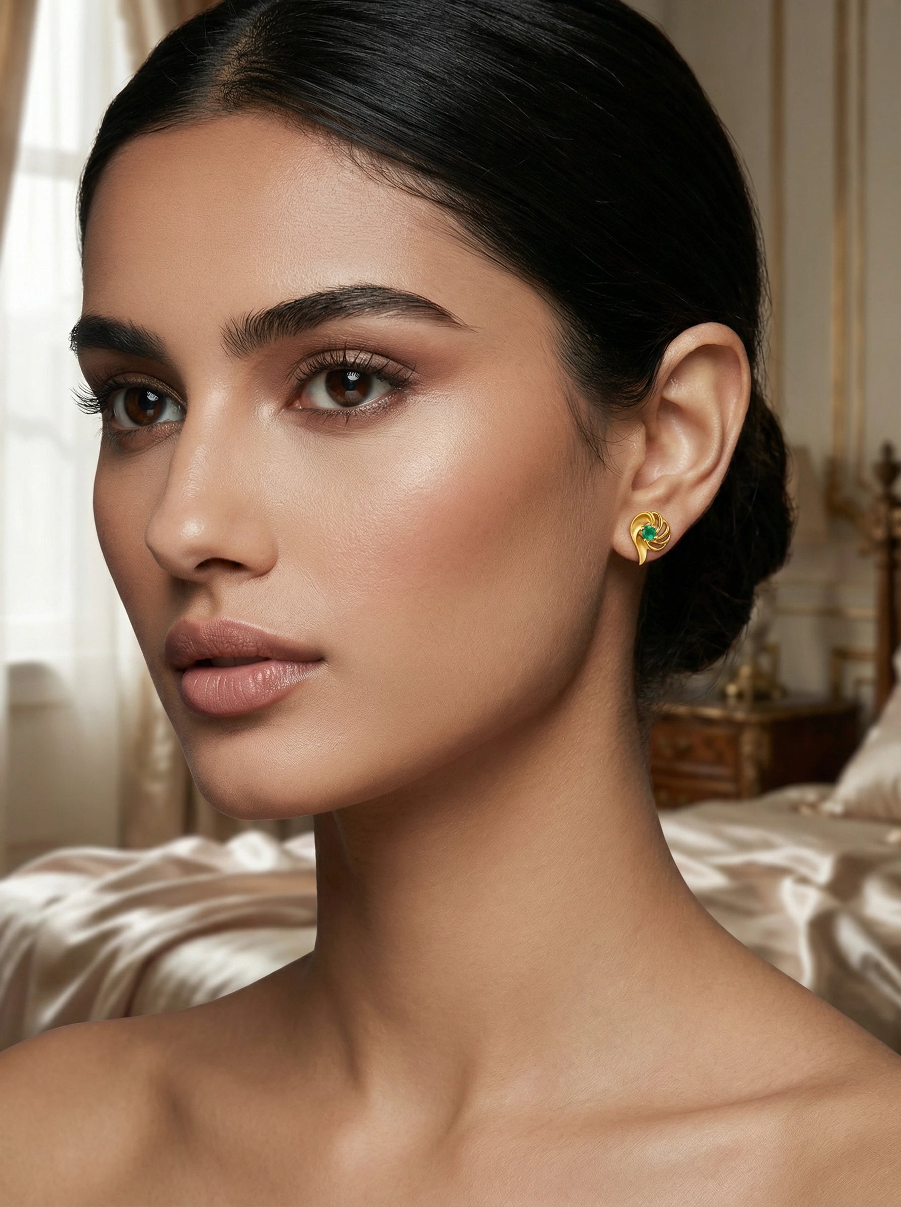 Woman wearing a 18k gold plated earring with a green gemstone in an elegant room setting