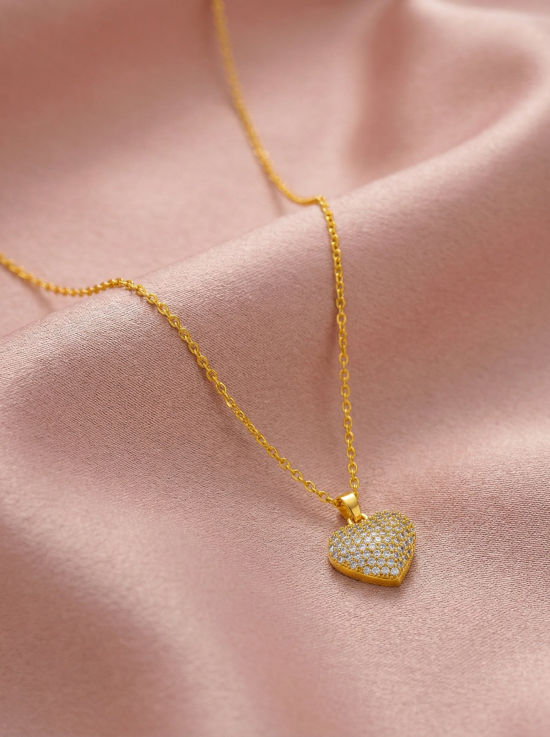 18k Gold plated heart-shaped pendant necklace on a pink fabric background