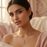 Woman wearing a 18k gold plated necklace with a heart pendant in a soft, blurred indoor setting
