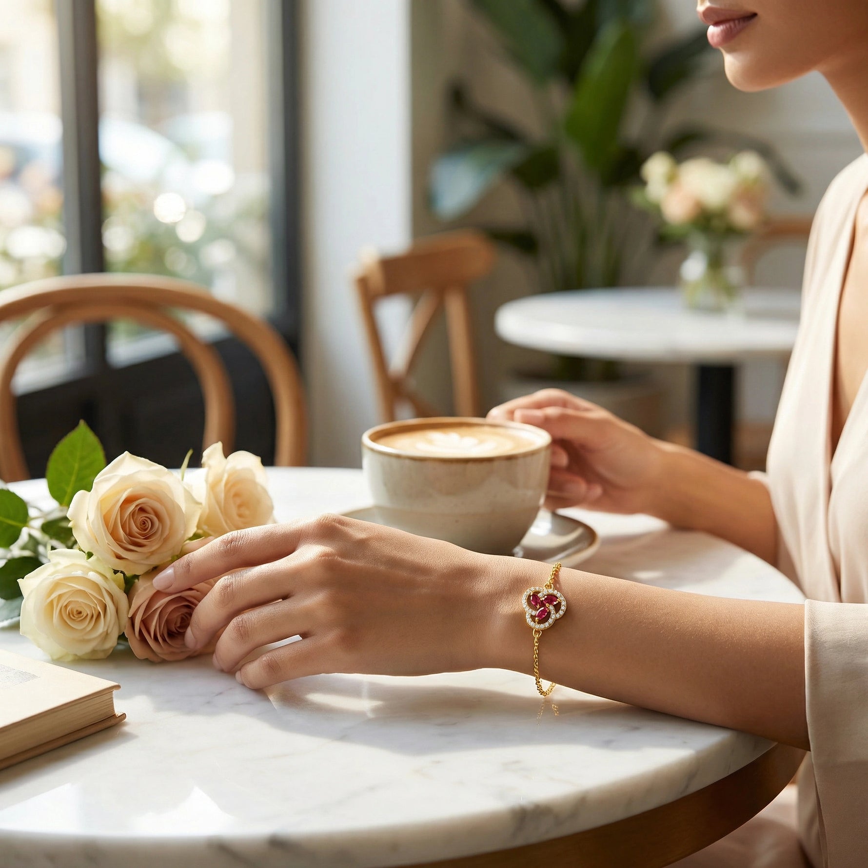 wear 18k gold plated bracelet Person holding a cup of coffee with flowers on a table in a cafe.