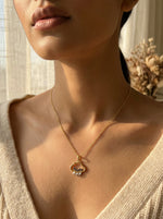 Close-up of a person wearing a 18k gold plated necklace with a heart-shaped pendant.