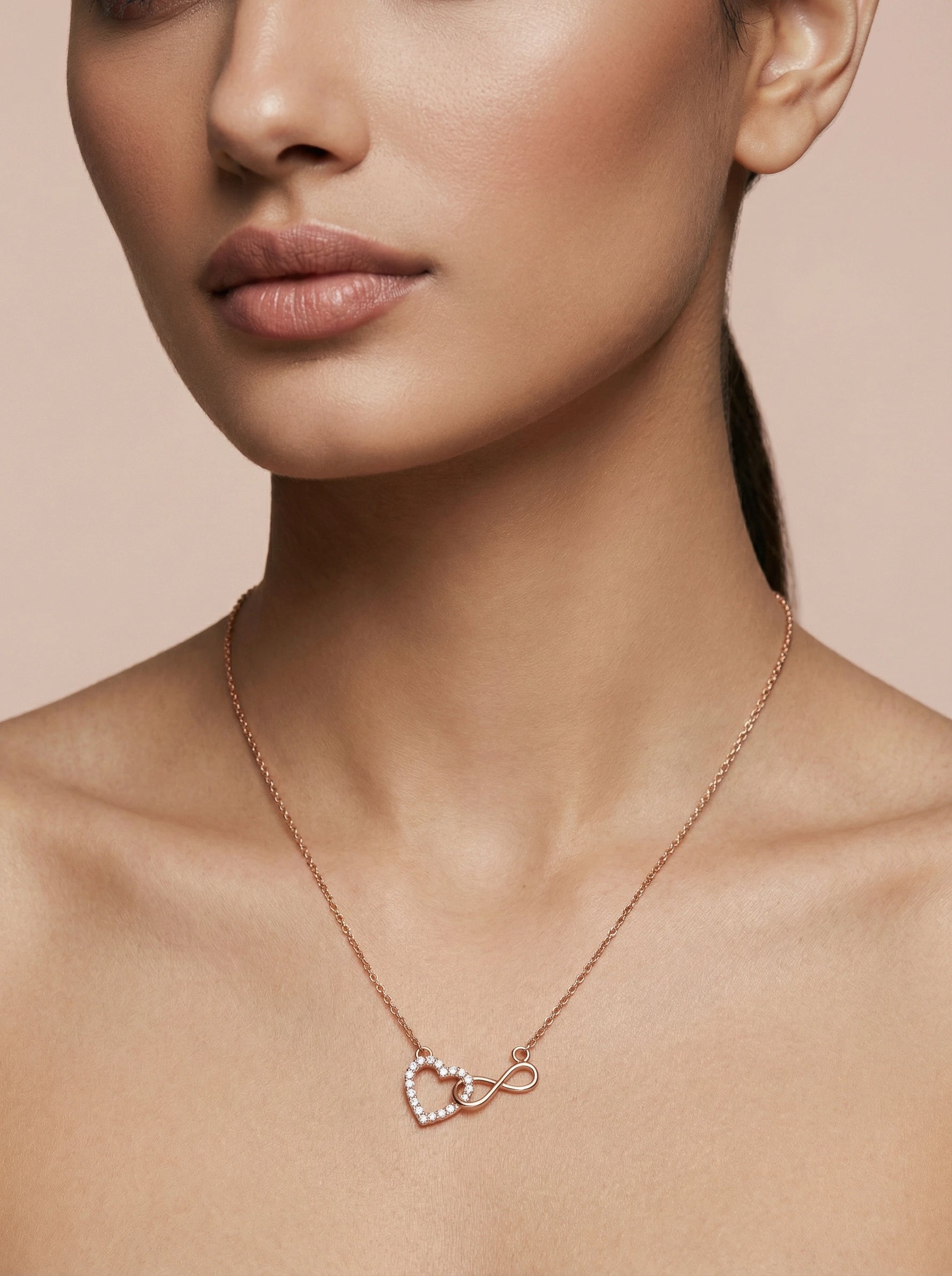 18k Rose gold plated necklace with heart and infinity symbol on a model against a beige background