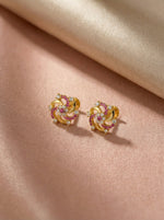 18k Gold plated earrings with pink gemstones on a beige fabric background