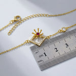 18k Gold plated bracelet with a decorative clasp next to a ruler on a light gray background