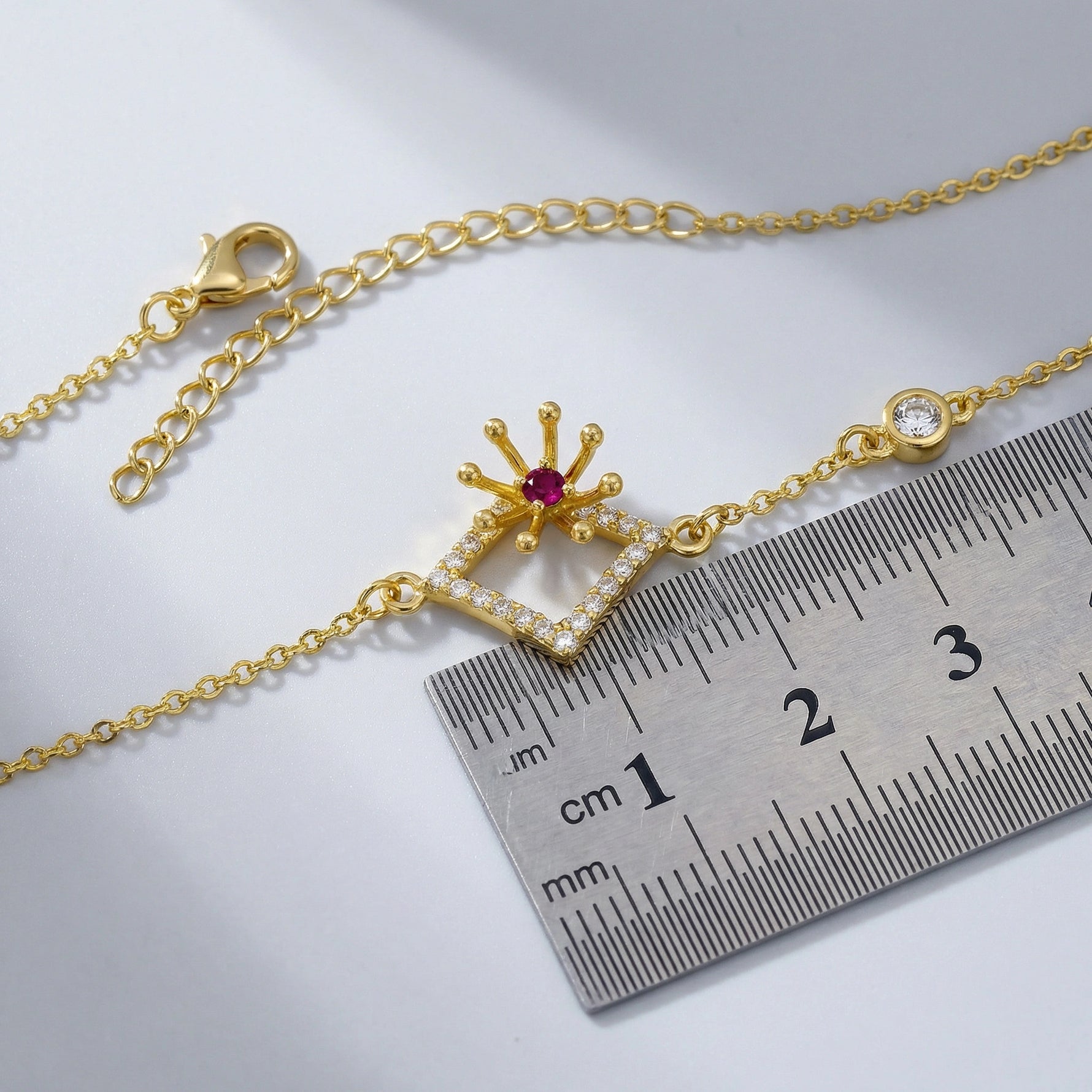 18k Gold plated bracelet with a decorative clasp next to a ruler on a light gray background