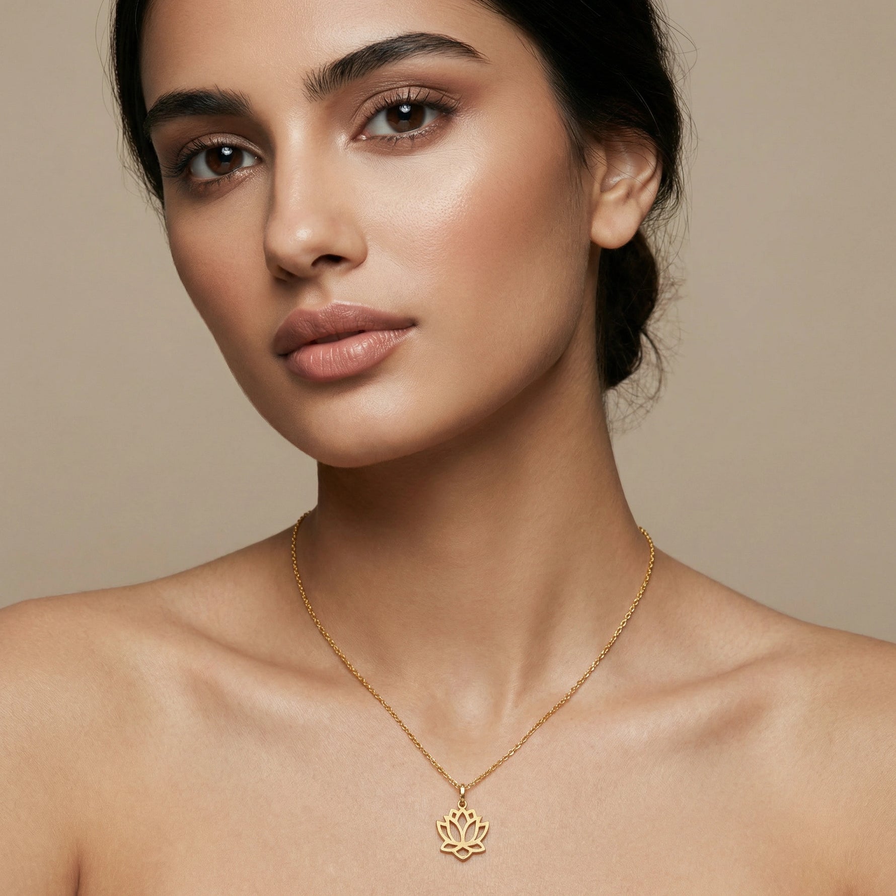 Woman wearing a 18k gold plated necklace with a lotus pendant against a beige background