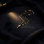 18k Gold plated key necklace on a dark fabric background
