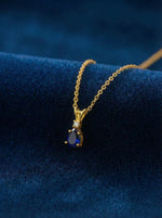 18k Gold plated necklace with a blue gemstone pendant on a blue fabric background