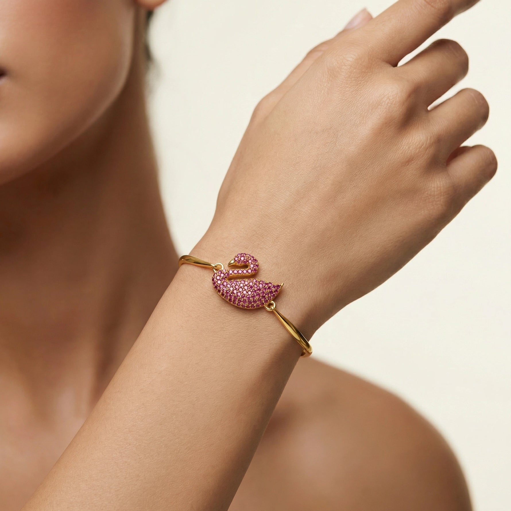 18k Gold plated bracelet with pink gemstones on a person's wrist against a neutral background