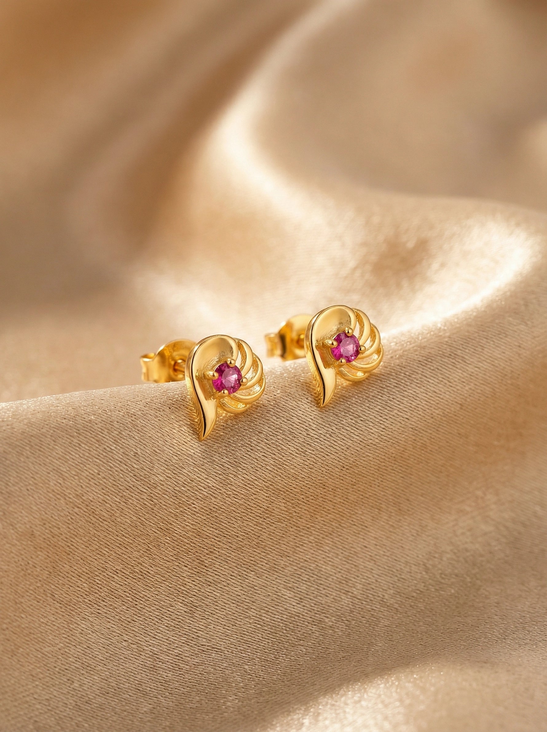 18k Gold plated earrings with pink gemstones on a beige fabric background