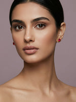Close-up of a woman wearing 18k gold plated red earrings against a neutral background