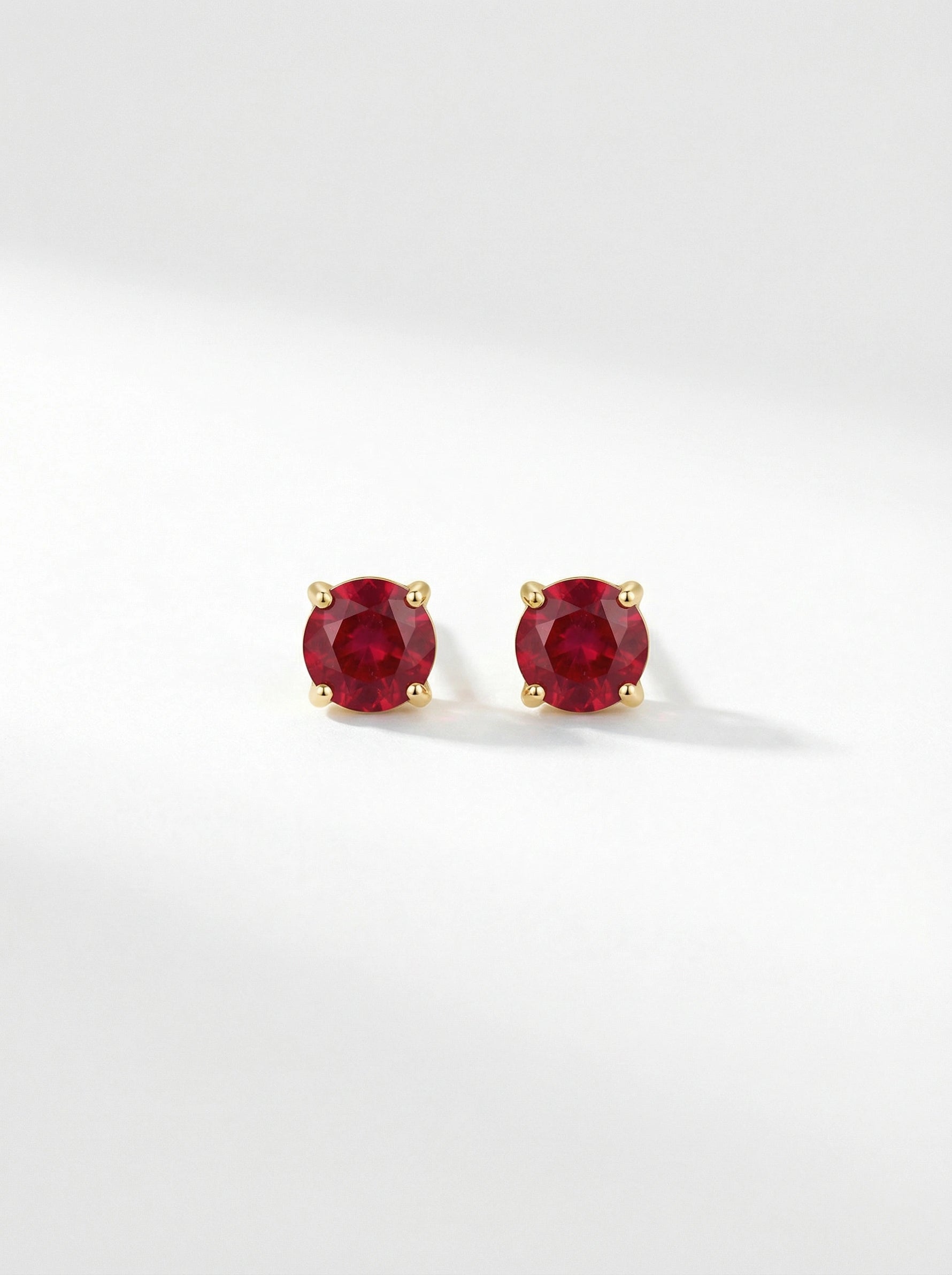 Pair of18k gold plated  red gemstone stud earrings on a white background