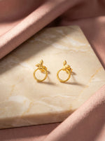 18k Gold plated earrings on a marble surface with a soft pink fabric background