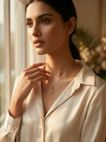 Woman wearing 18k gold plated  necklace in a softly lit room with a window in the background