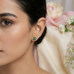 Close-up of a woman wearing green 18k gold plated earrings with a blurred floral background