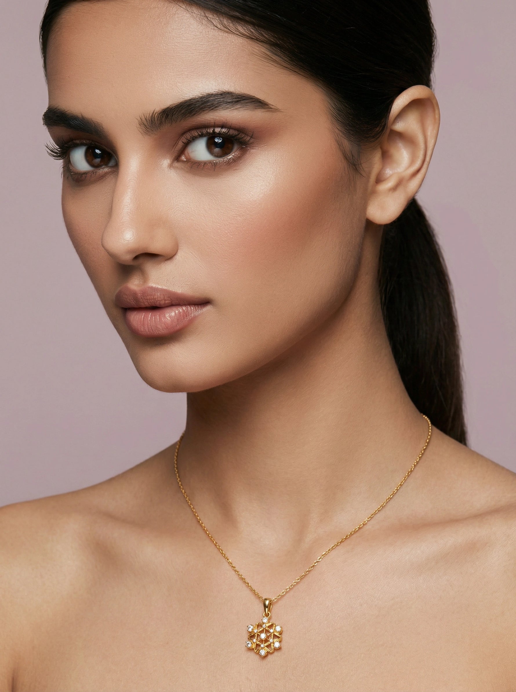 Woman wearing a 18k gold plated necklace with a pendant against a pink background