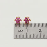 18k Gold plated earrings with pink gemstones next to a ruler for size reference on a white background