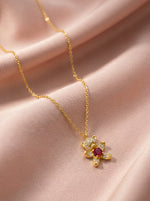 18k Gold plated necklace with a red gemstone pendant on a pink fabric background