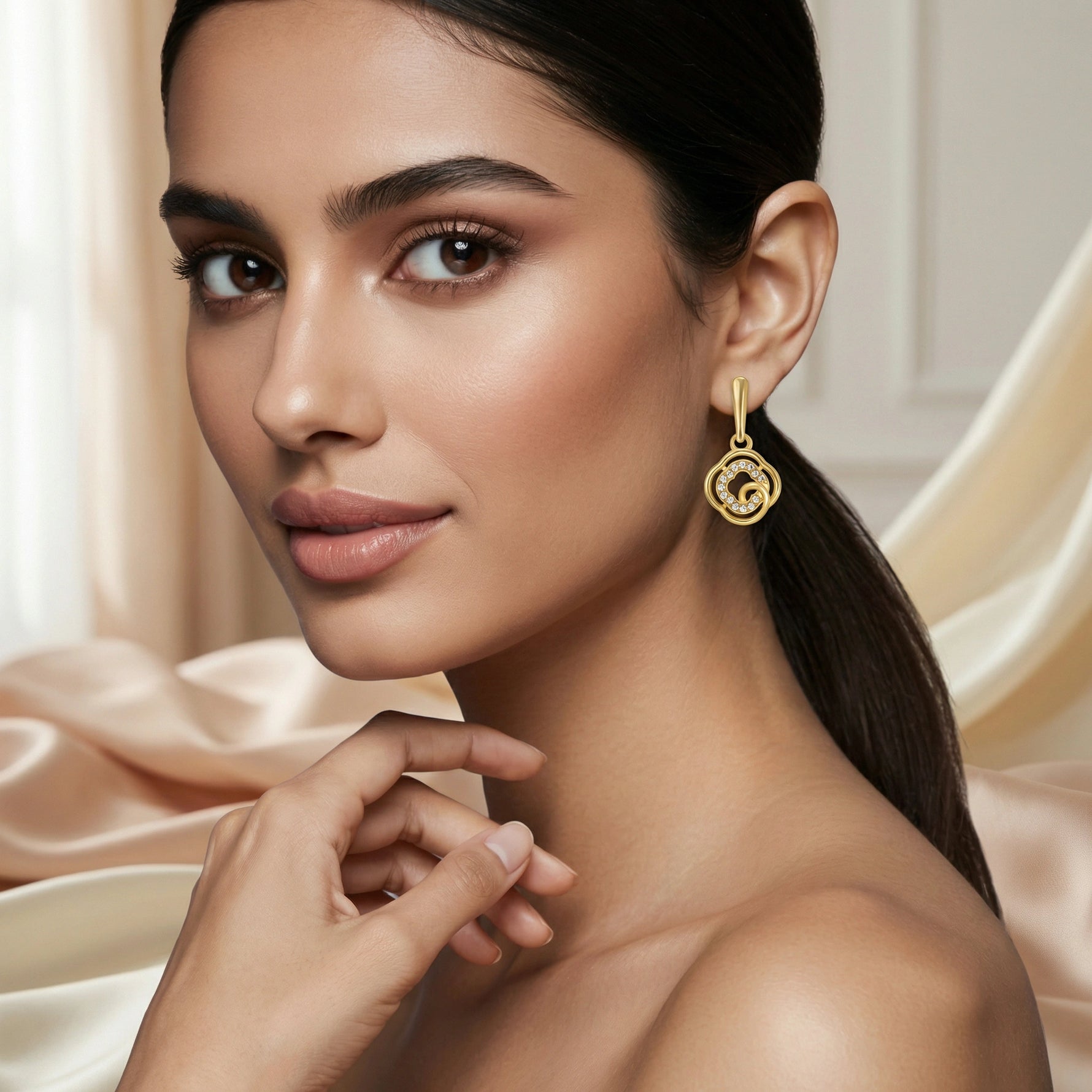 Woman wearing 18k  gold plated earrings with a neutral background