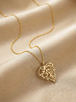 18k Gold plated necklace with a leaf pendant on a beige fabric background