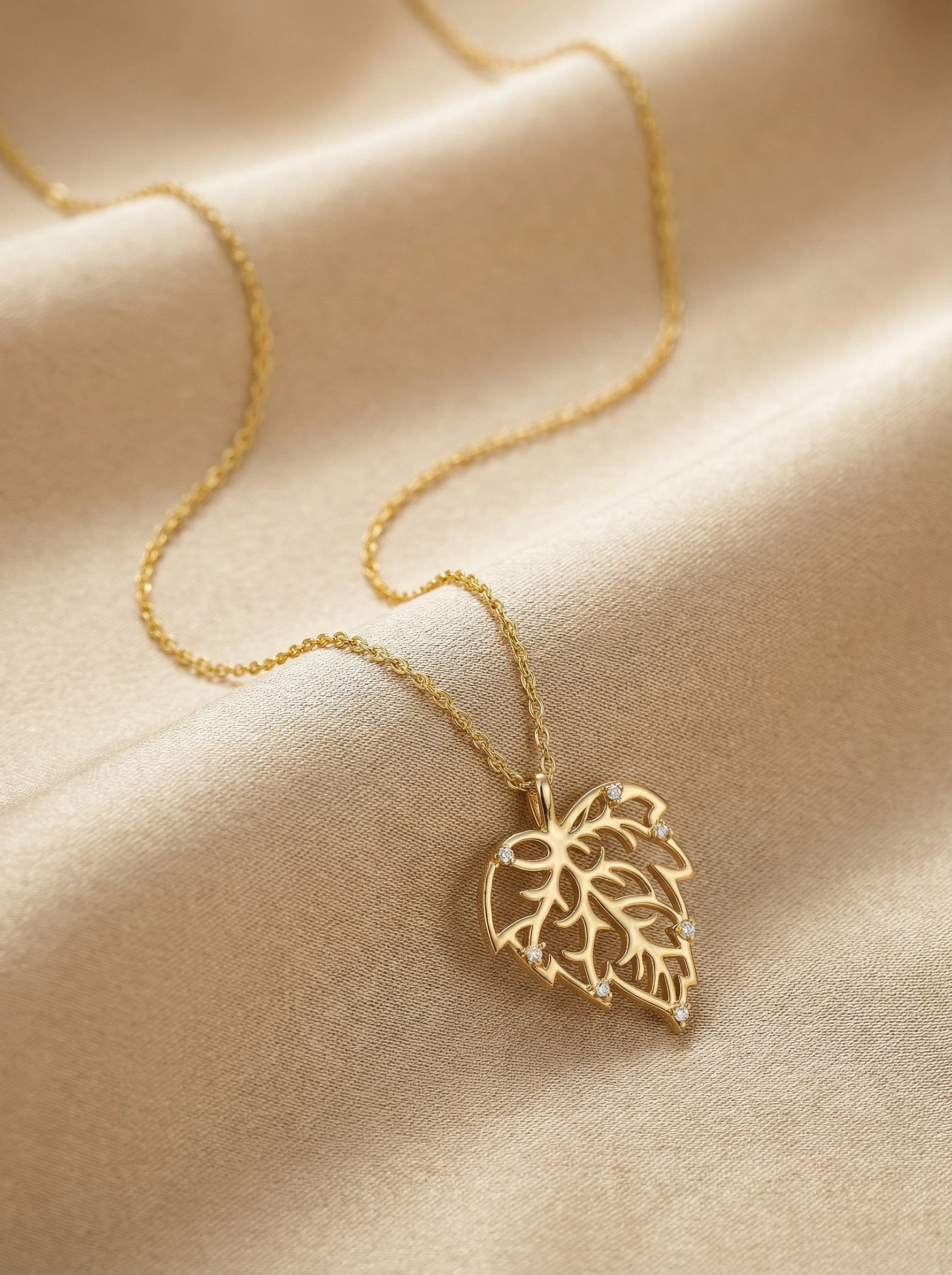 18k Gold plated necklace with a leaf pendant on a beige fabric background