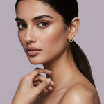 Woman wearing a 18k gold plated heart-shaped earring against a light purple background