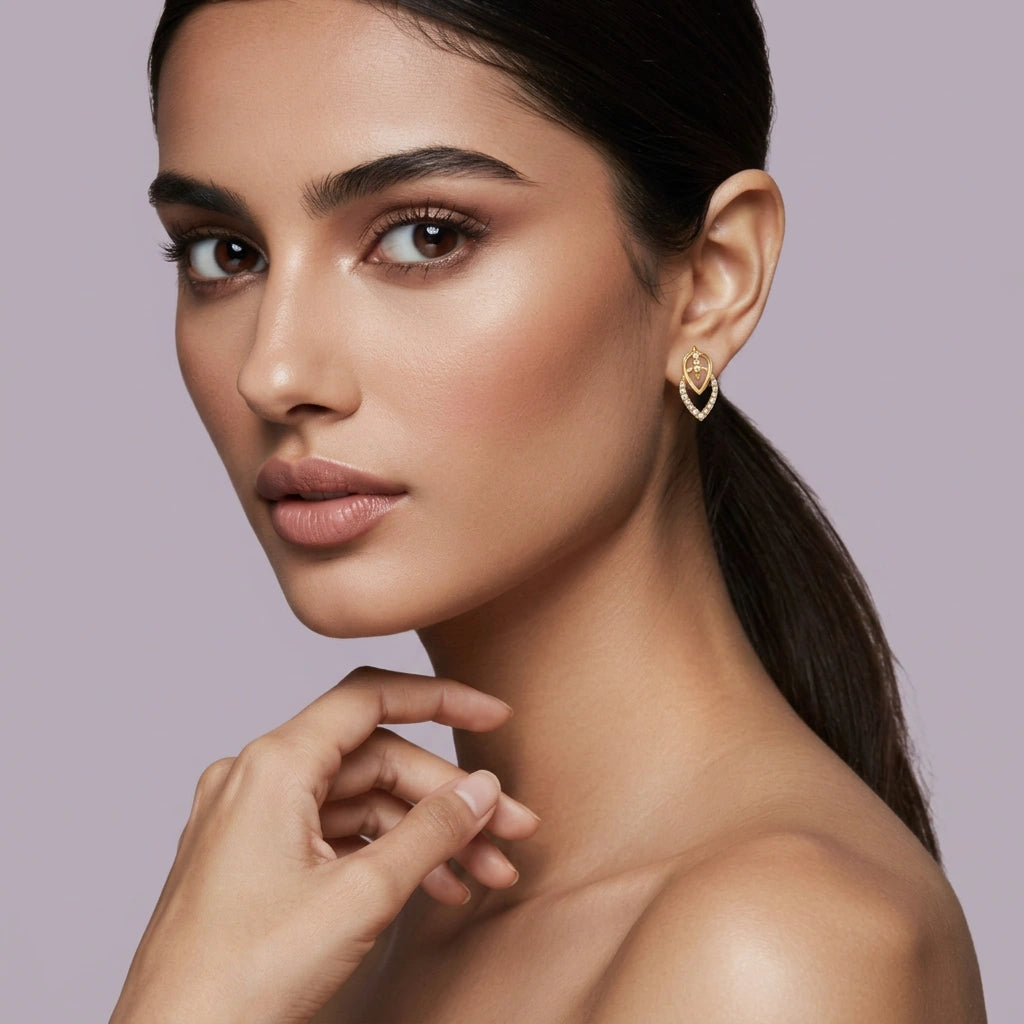 Woman wearing a 18k gold plated heart-shaped earring against a light purple background