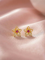 18k Gold plated earrings with red gemstones on a pink fabric background