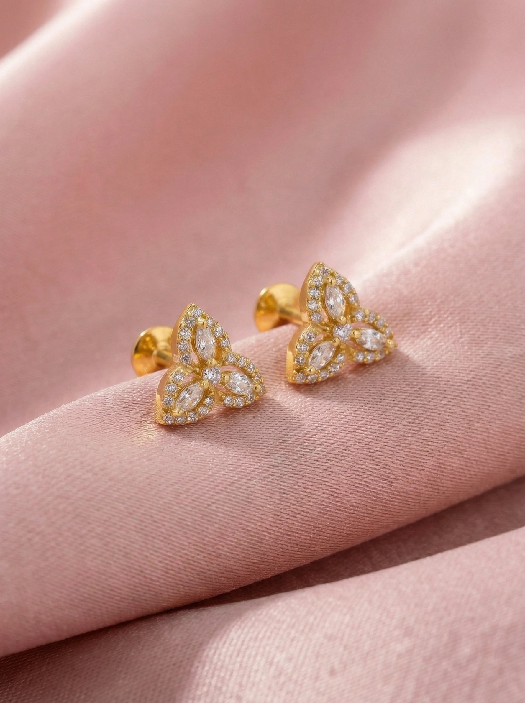 18k Gold plated fearrings with diamond accents on a pink fabric background