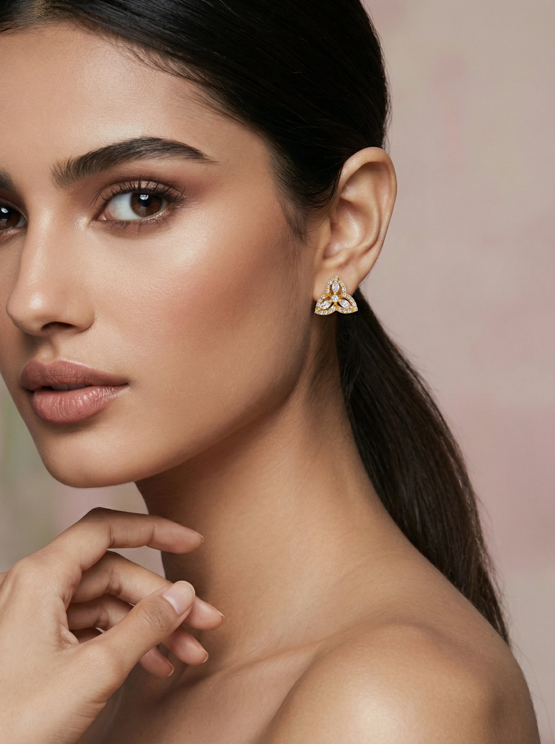 Woman wearing 18k gold plated earrings with a soft background