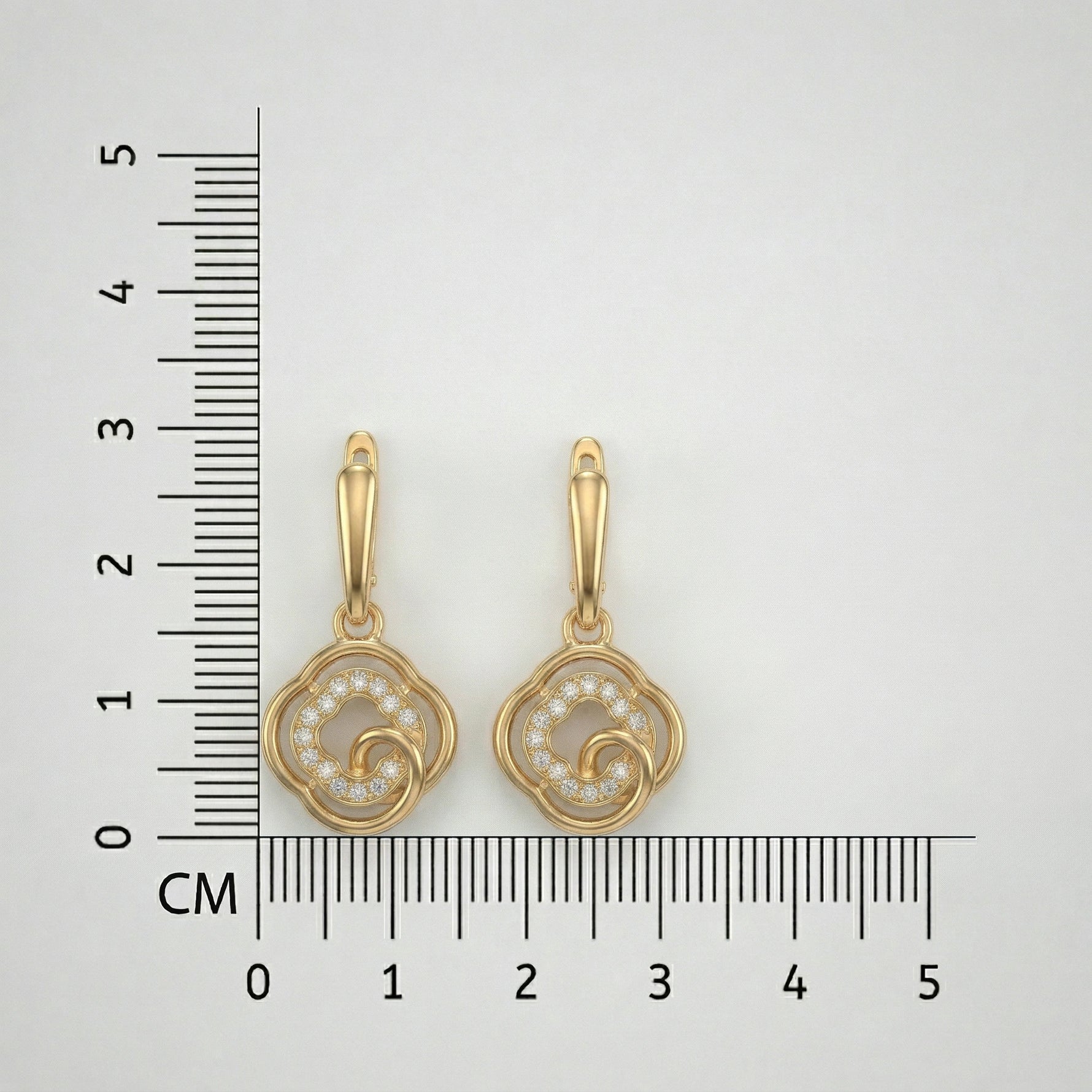 18k Gold plated earrings with intricate design next to a ruler for scale on a white background