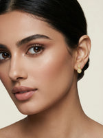 Close-up of a woman wearing 18k gold plated earrings with a neutral background