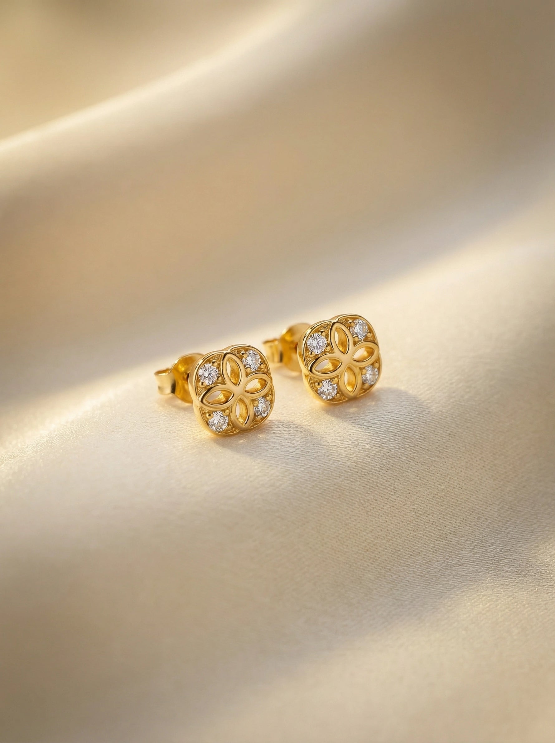 18k Gold plated earrings with diamond accents on a beige background